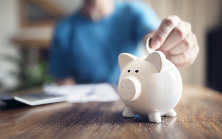 man putting money in a piggy bank