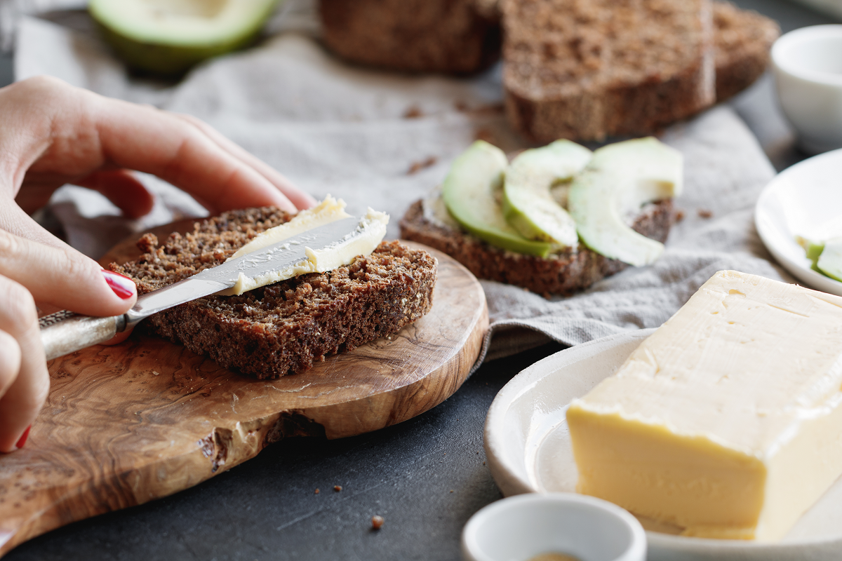 The girl is preparing toast from rye bread and butter for breakfast