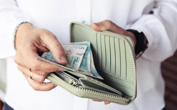 Close up of hand of woman taking out pounds from her purse