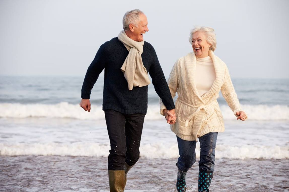 mature couple together on beach in wellies