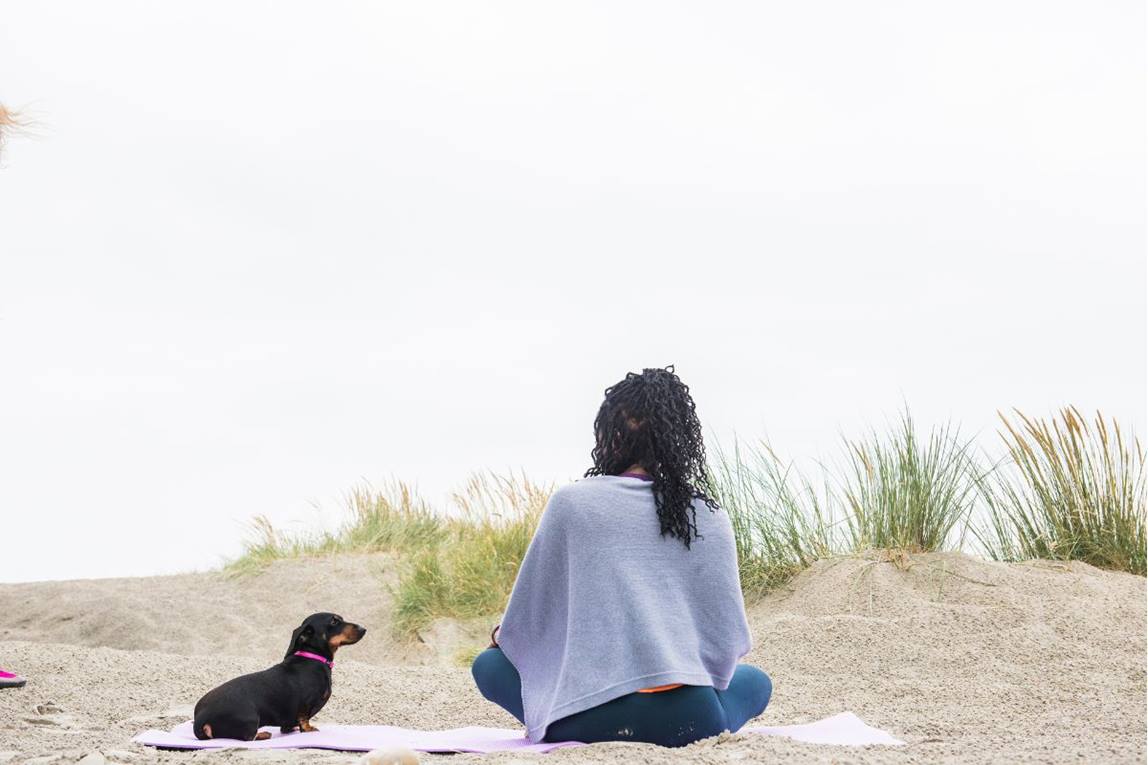 women sat on sandy each with Stanley the sausage dog