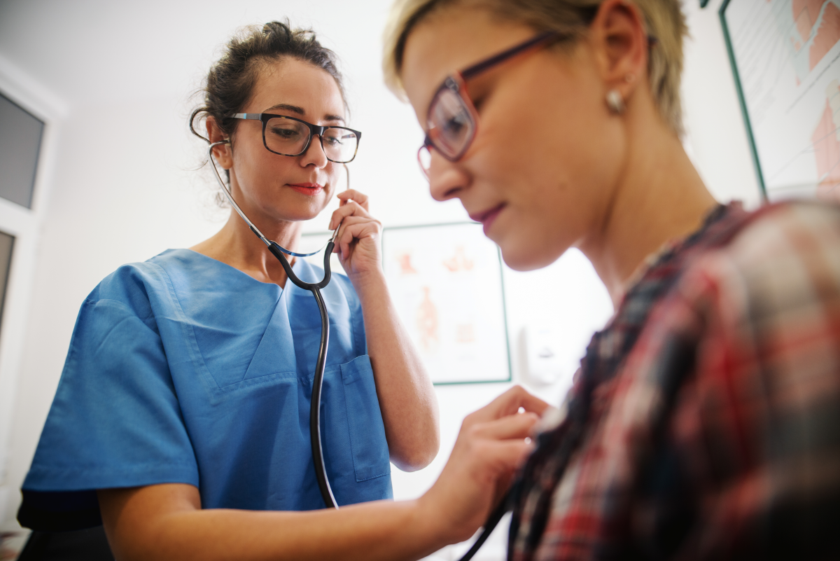 Female middle-aged doctor using stethoscope to examine patient